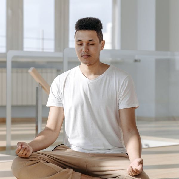 Person meditating in a bright, minimalist room, symbolizing mental peace.
